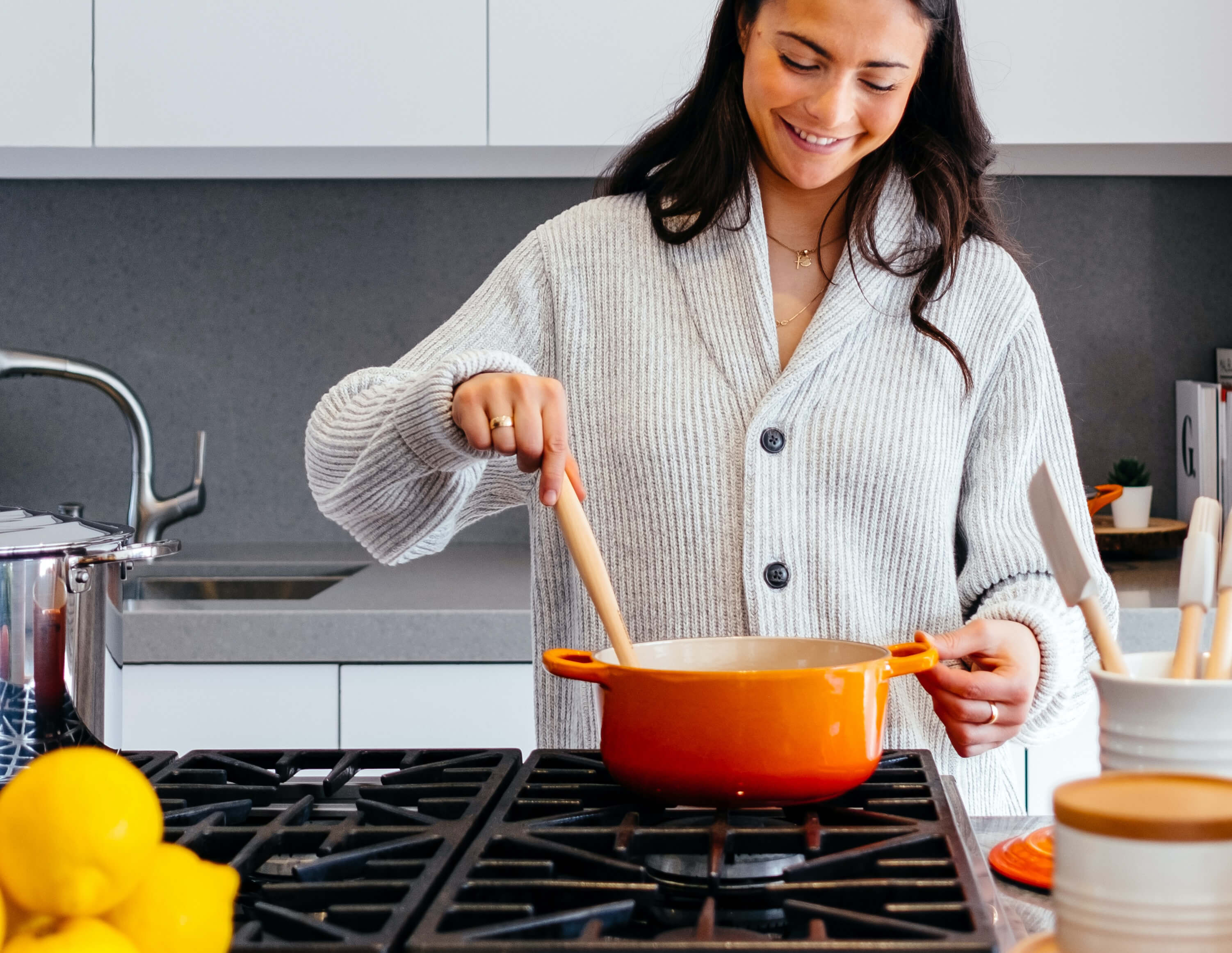 A woman cooking with gas heat on a cooktop in a remodeled kitchen.