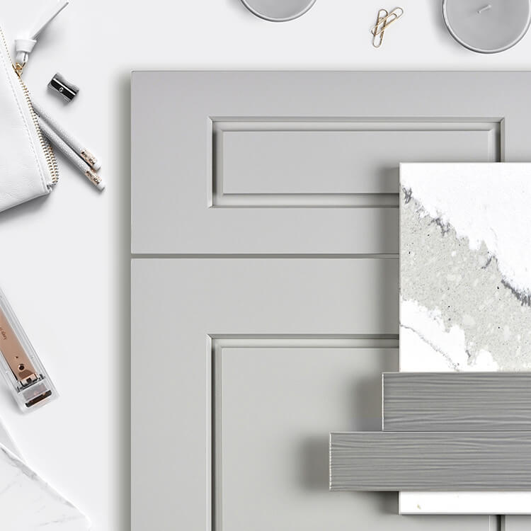 A flat lay showing a kitchen design mood board with an all gray color palette using a modern raised panel door with a gray painted finish as well as gray and white tiles and countertop samples.