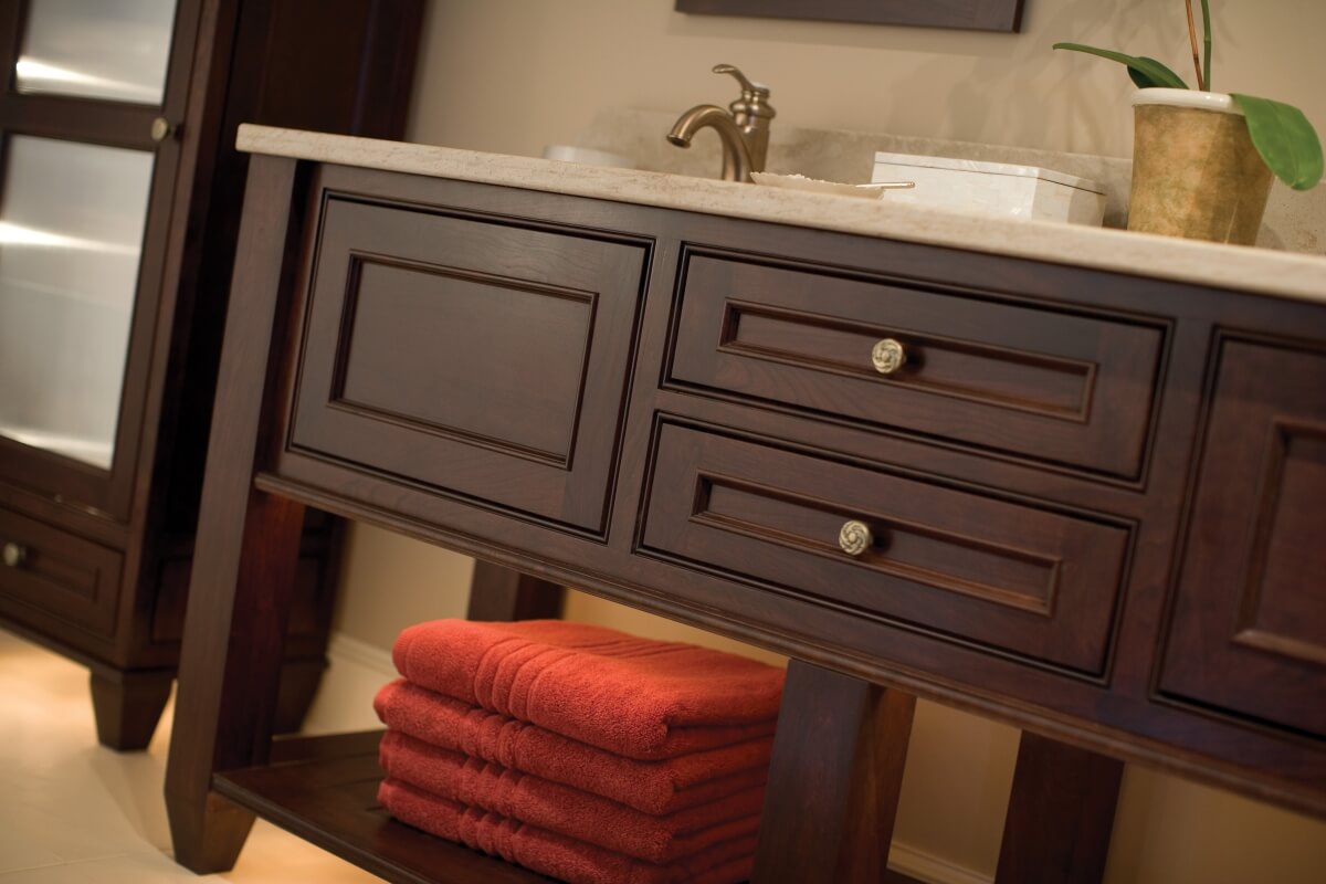 A bathroom vanity by Dura Supreme Cabinetry with an open shelf by the floor for storing towels and other everyday items.
