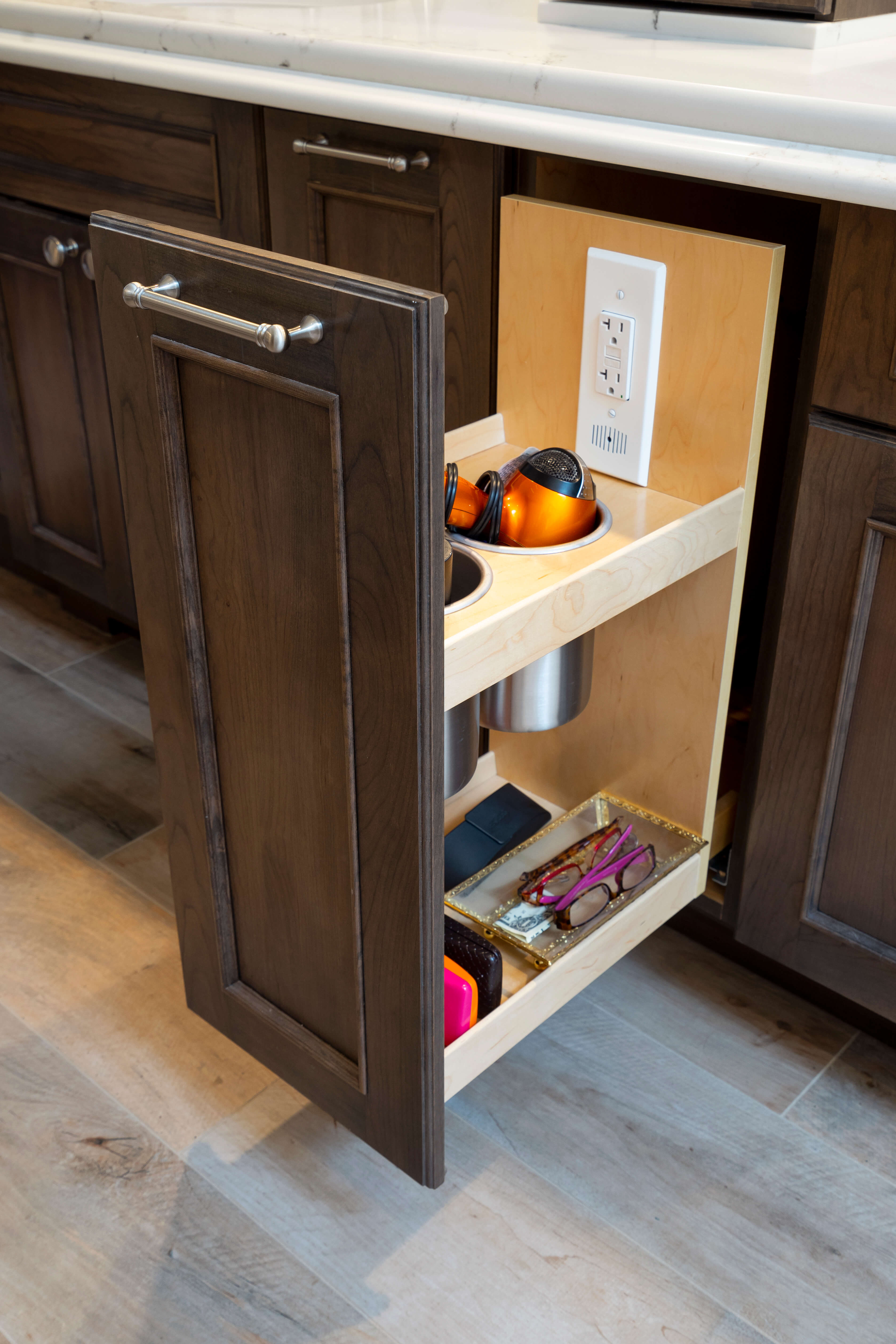 A bathroom vanity pull-out cabinet with an outlet for hairdriers, curling irons, and more.
