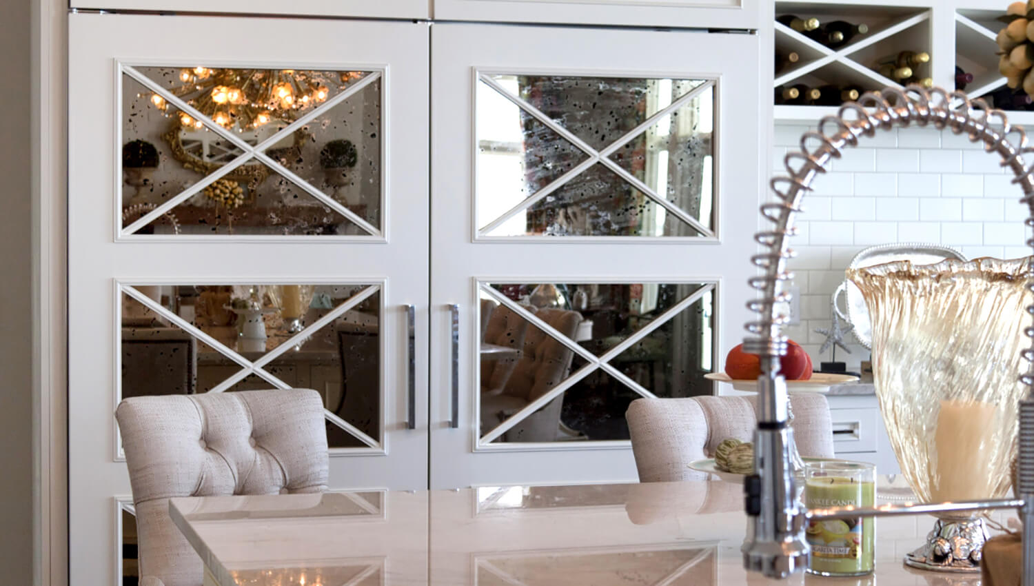 A cabinet paneled French door refrigerator with mirrored mullion insets to hide the large kitchen appliance.