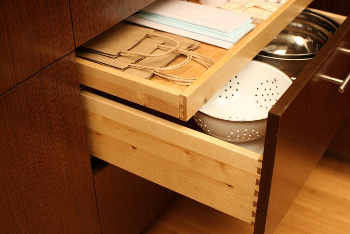 A roll-out above drawer storing lunch bags, and misc. kitchen items above a deep drawer with mixing bowls. Dura Supreme Cabinetry has a large variety of kitchen storage soutions.
