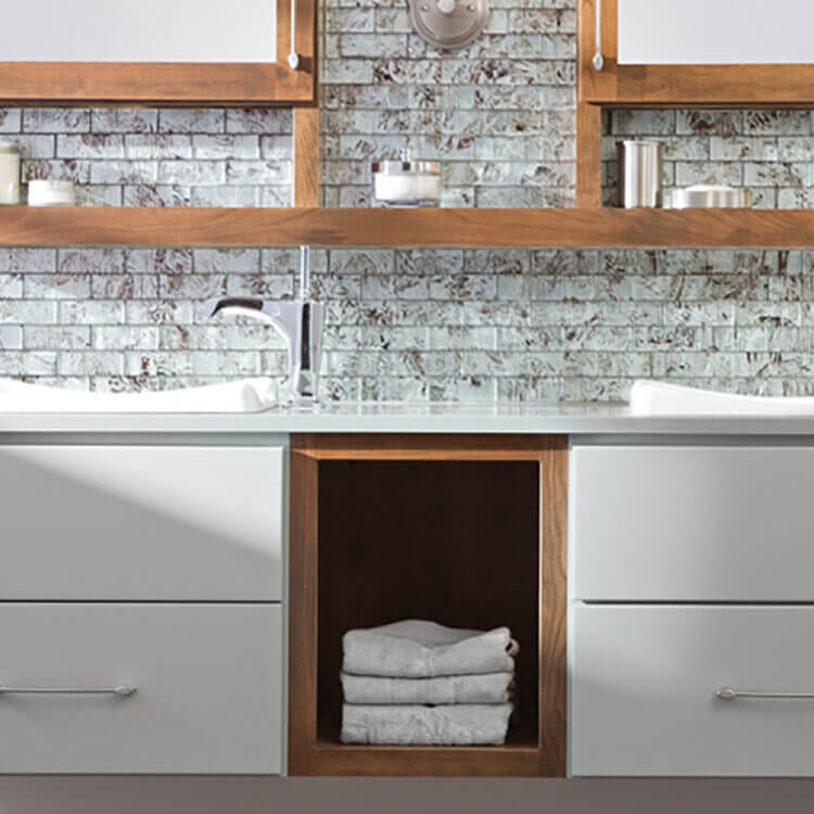 A two-toned floating vanity with light gray paint and warm stained wood with open storage and a floating shelf connecting to the dual medicine cabinets with a modern design.