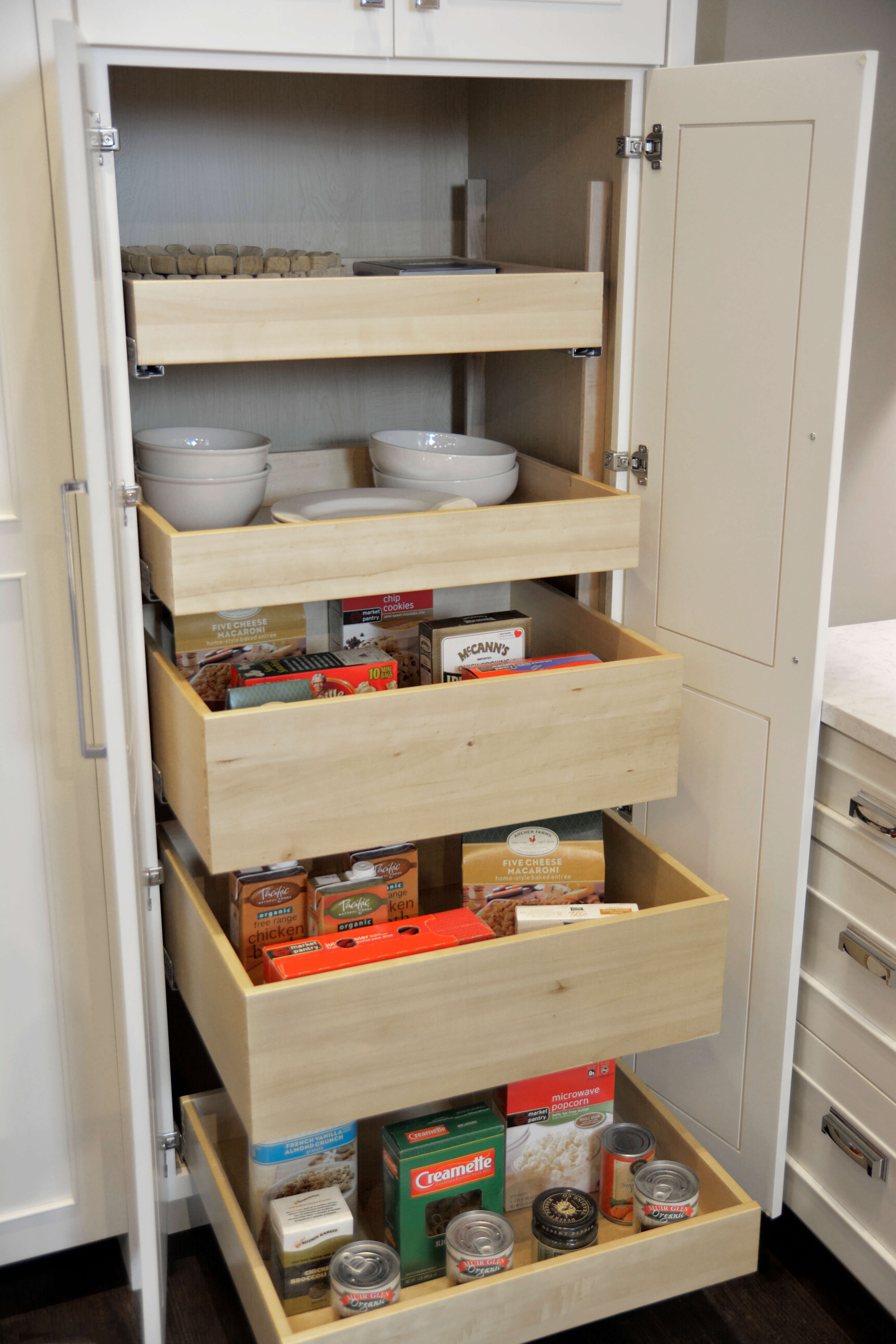 A tall kitchen pantry cabinet with roll-out shelves for easy and accessible storage for kitchen supplies and dry goods.