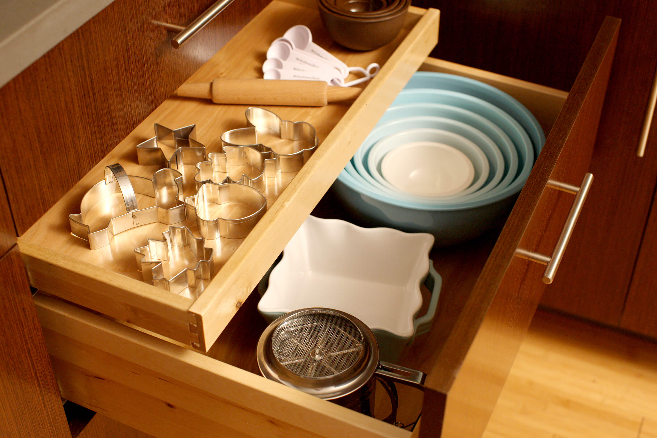 Keep all your baking supplies in one spot by using a deep drawer for mixing bowls with a small roll-out tray for your cookie cutters and misc. baking tools.