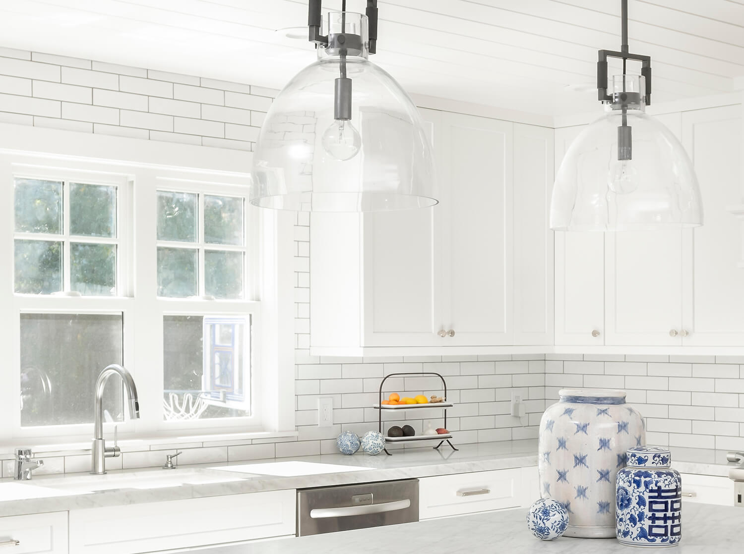 Bright white kitchen cabinets with white marble countertops.