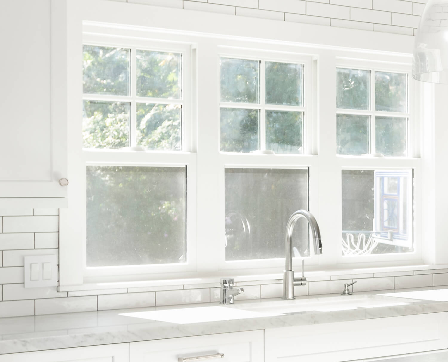 Bright white kitchen cabinets with white marble countertops.