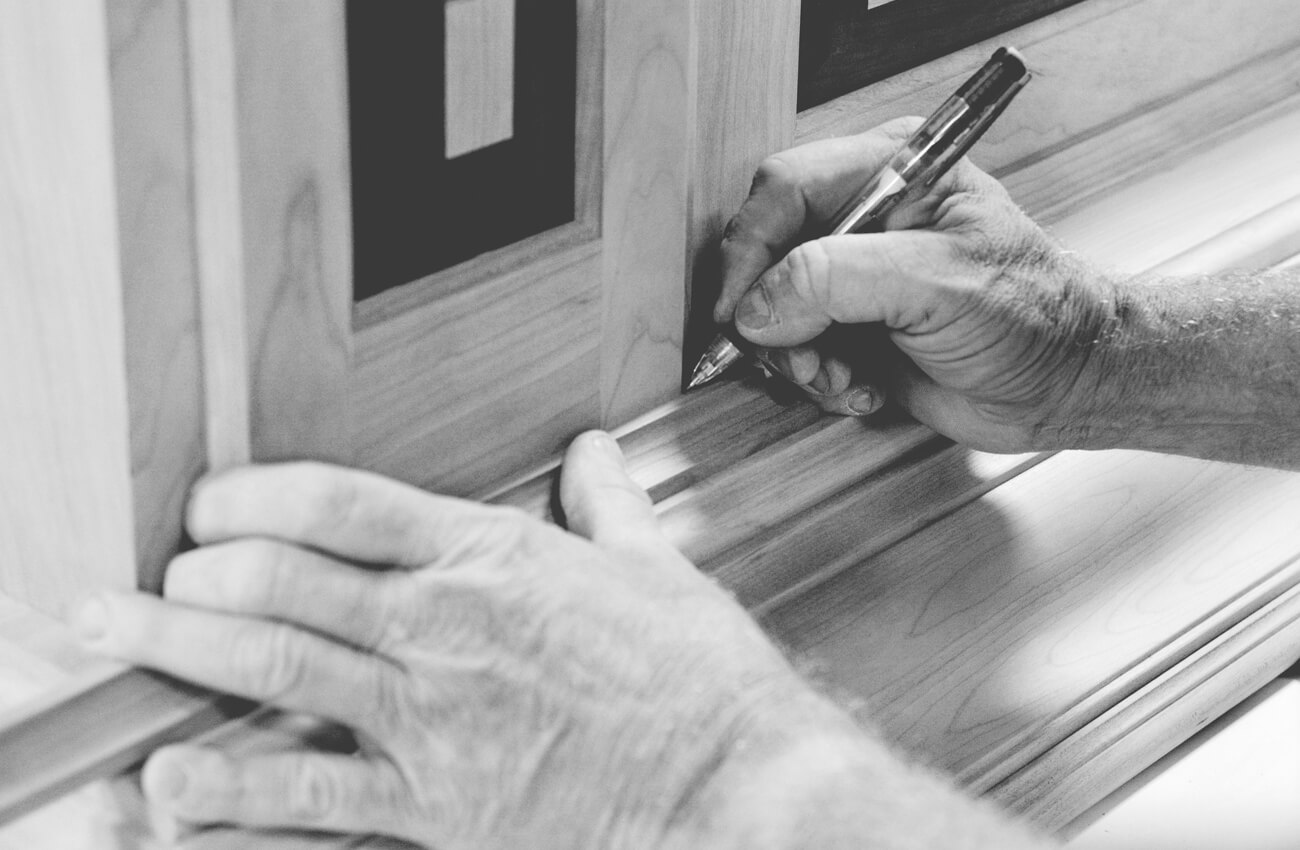 An expert craftsman working on the details of a kitchen wood hood at the Dura Supreme Cabinetry factory. Dura Supreme has fully custom capabilities at a semi-custom price point and has achieved awards in excellence for its manufacturing capabilities.