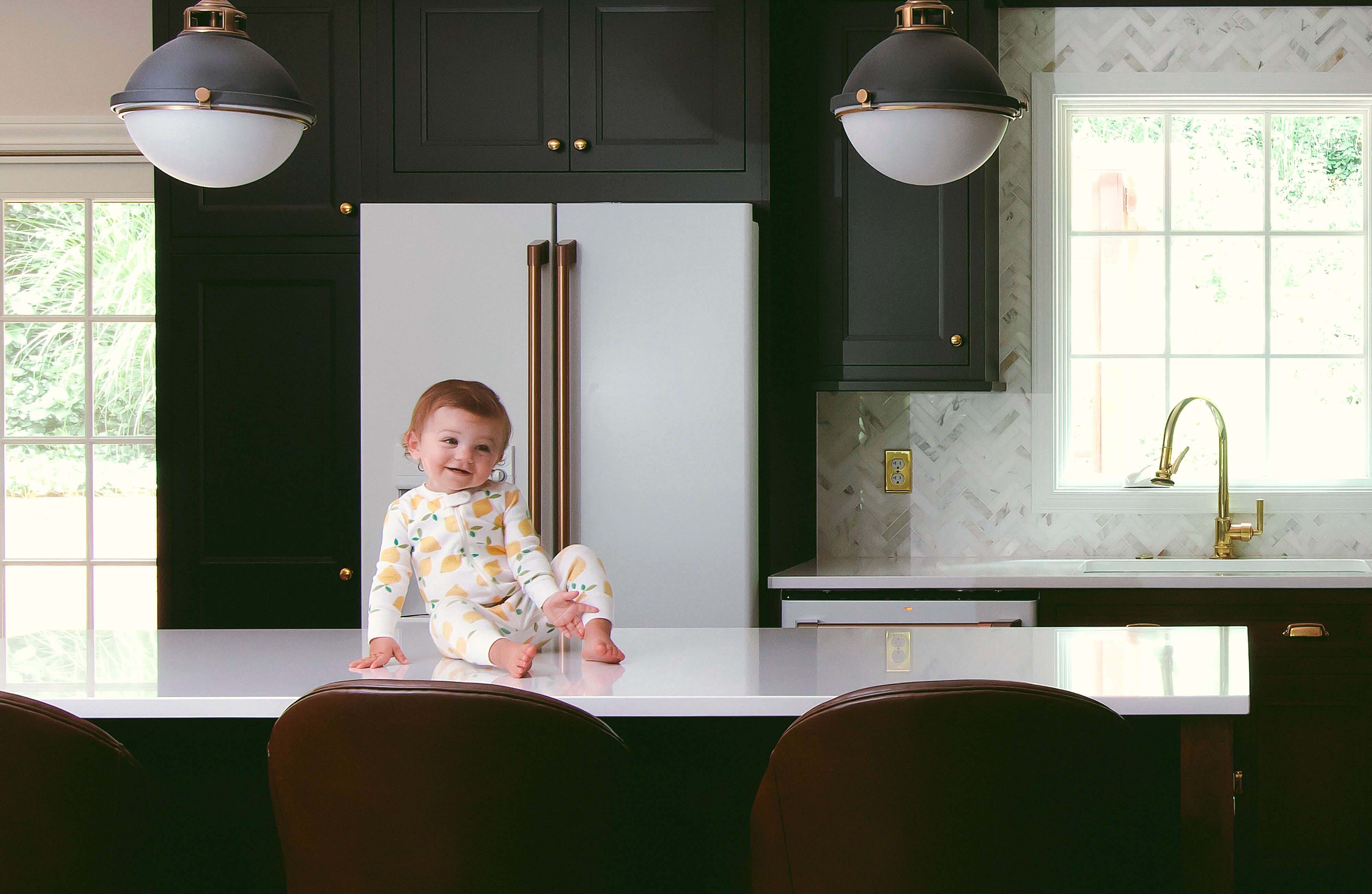 A black kitchen with white appliances with an adorable toddler happy to have a new kitchen!