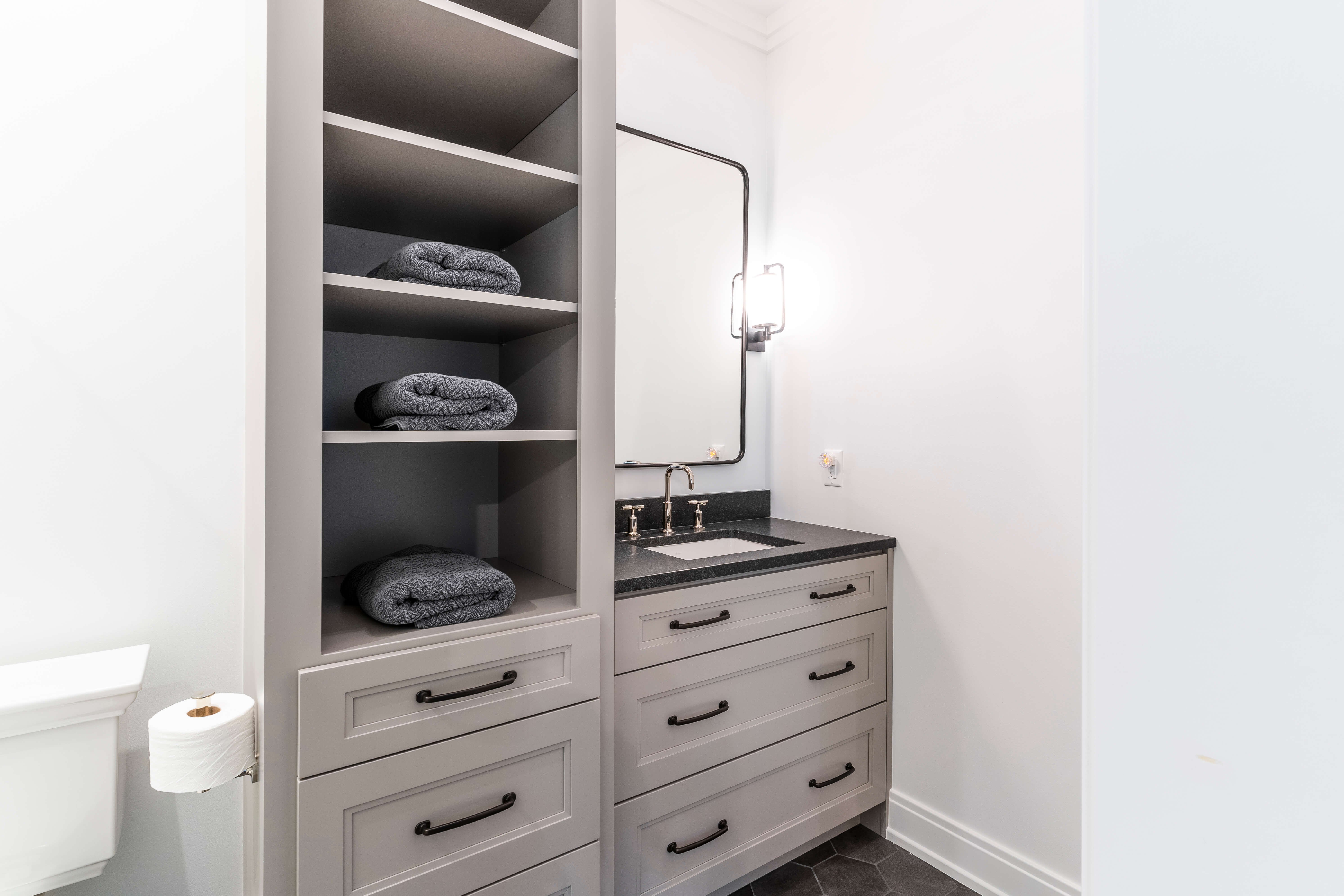 A bathroom with a tall tower for linen storage next to the sink.