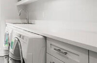 An all-white and bright laundry room with simple, sophisticated cabinets from Dura Supreme Cabinetry in a white painted finish.