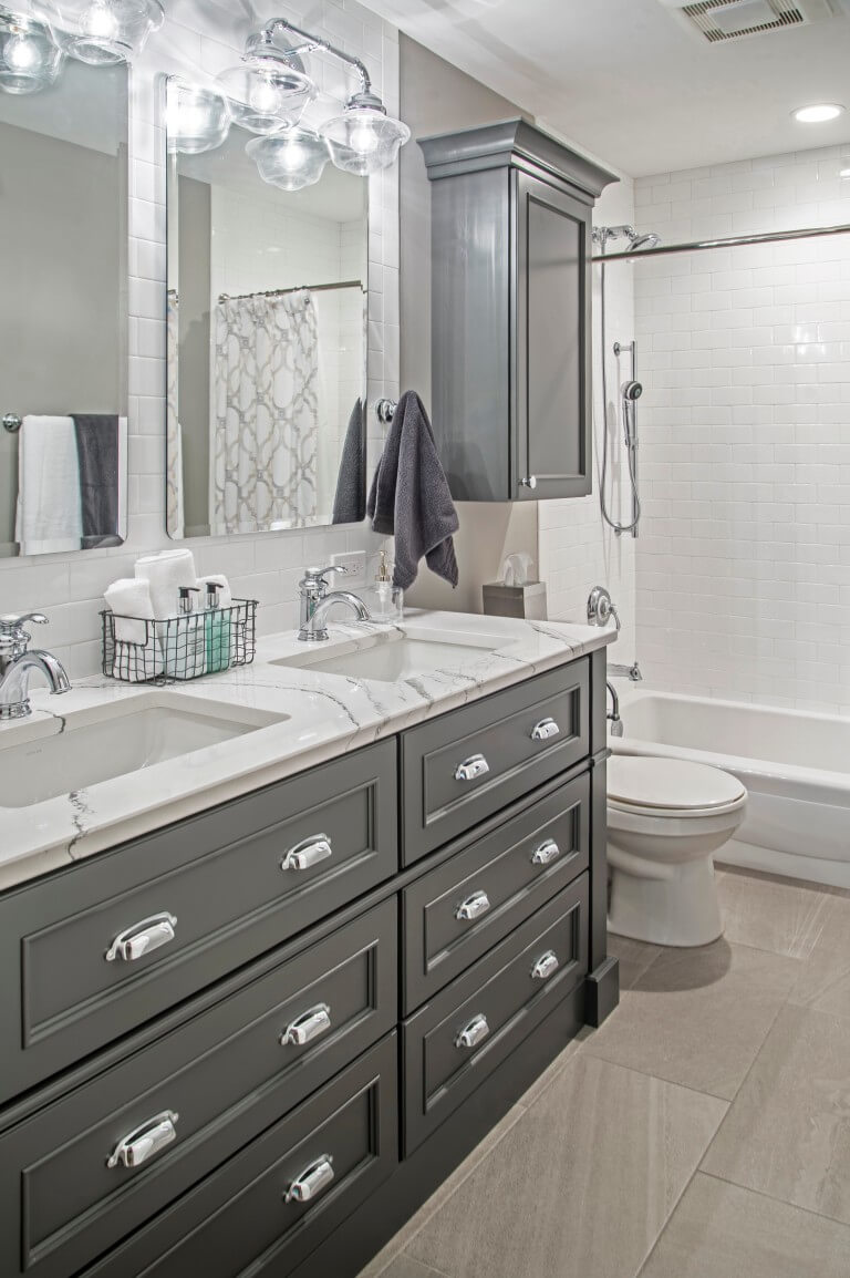A gray master bathroom with a dark gray painted vanity with double sinks and all drawers.