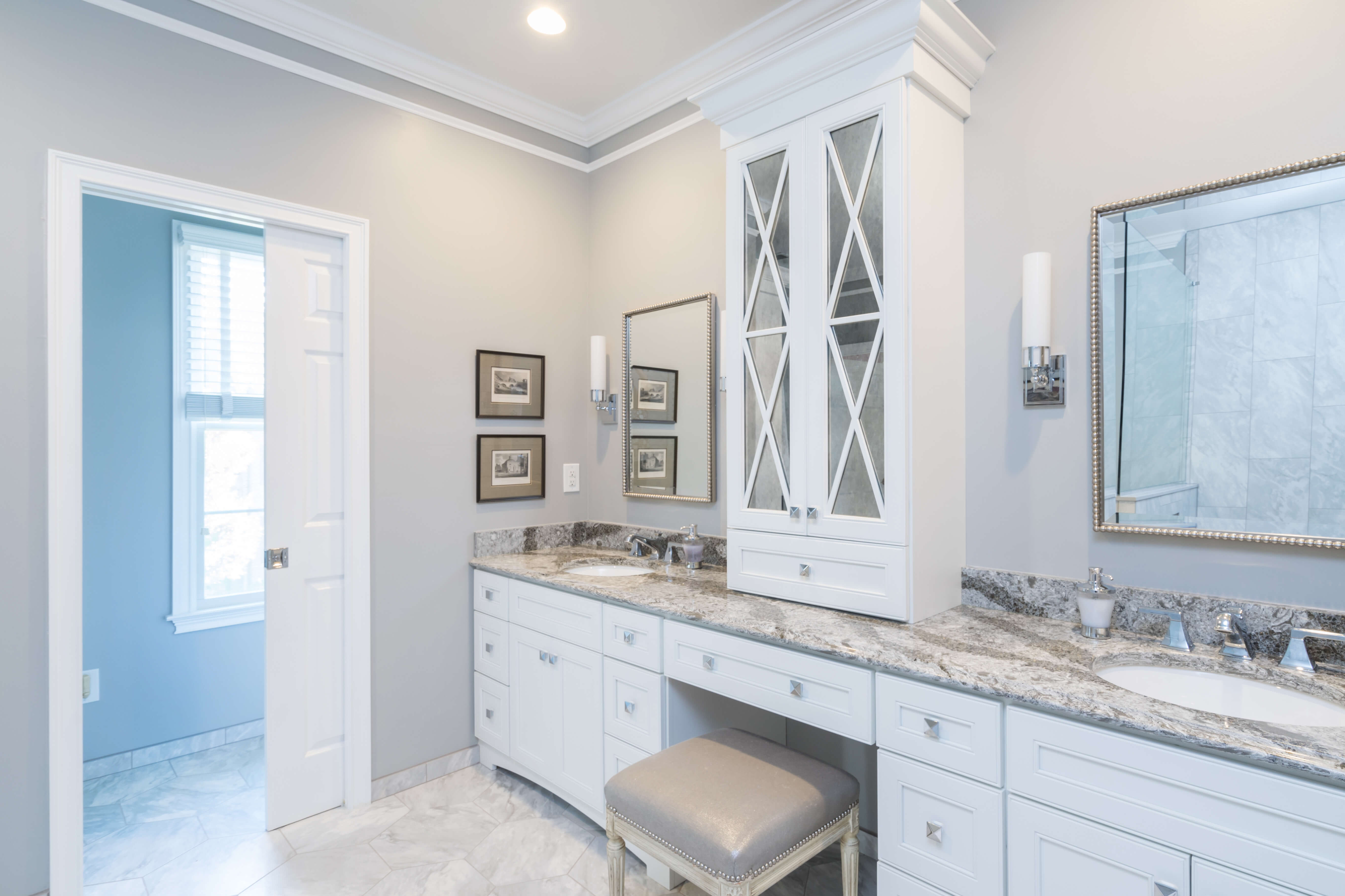A master bathroom with an all-white color palette and X-patterned mullion cabinet doors.