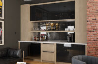 A modern home office with a wet bar area in an urban area with contemporary acrylic and white oak cabinets.