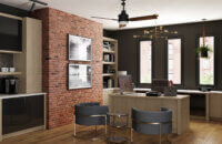 A home office or small urban office with a free standing desk and wall of cabinets next to an urban brick wall.