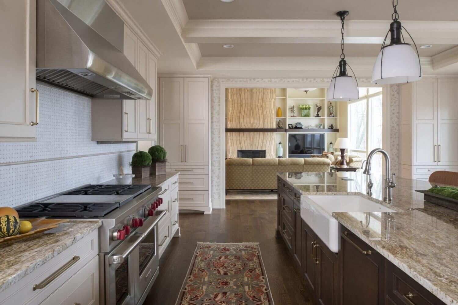 A look from the kitchen into the living room. The remodeled kitchen has white painted cabinets along the wall and a dark stained kitchen island.