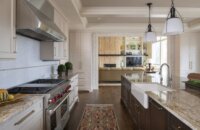 A look from the kitchen into the living room. The remodeled kitchen has white painted cabinets along the wall and a dark stained kitchen island.