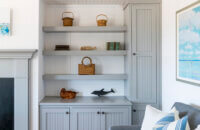 A gray painted built-in bookcase and cabinets match the fireplace mantel in this cottage style living room.