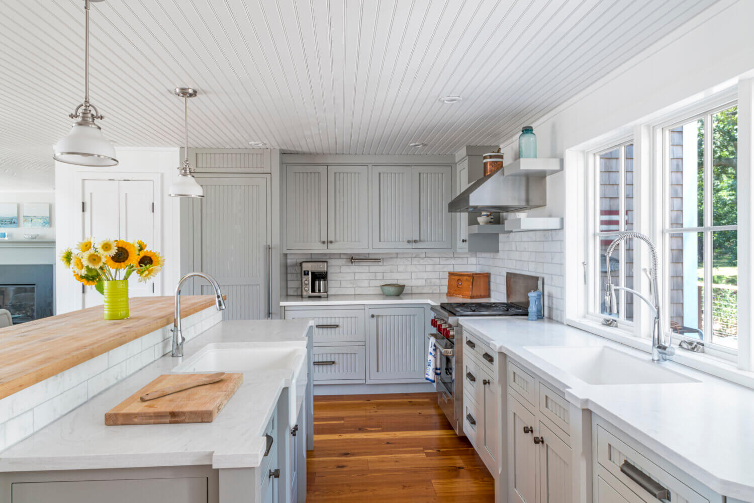 A gray and white cottage style kitchen with inset cabinets that have a beaded panel within the cabinet doors.