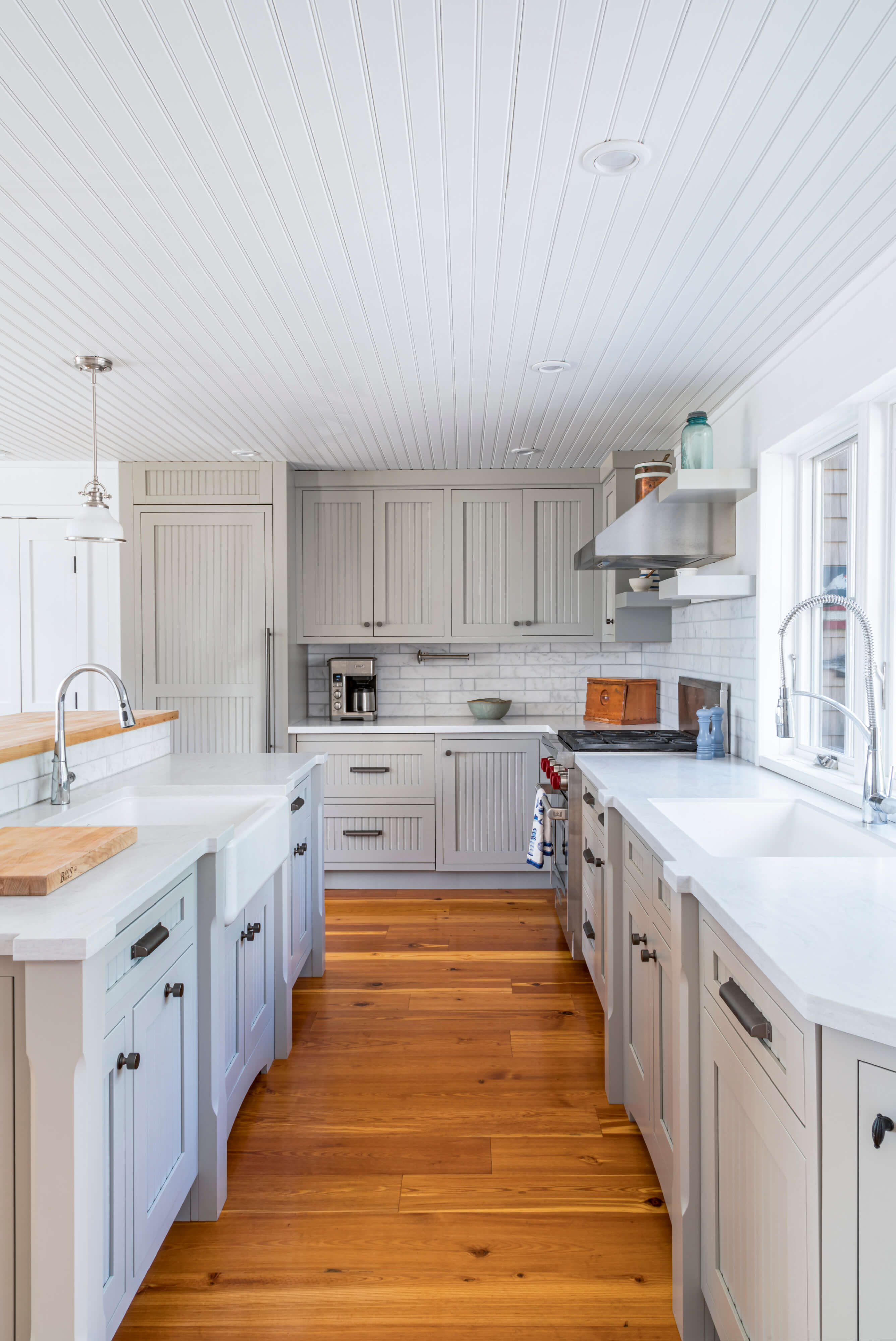 A delightful gray kitchen with cottage styled cabinet doors and a shiplap ceiling.