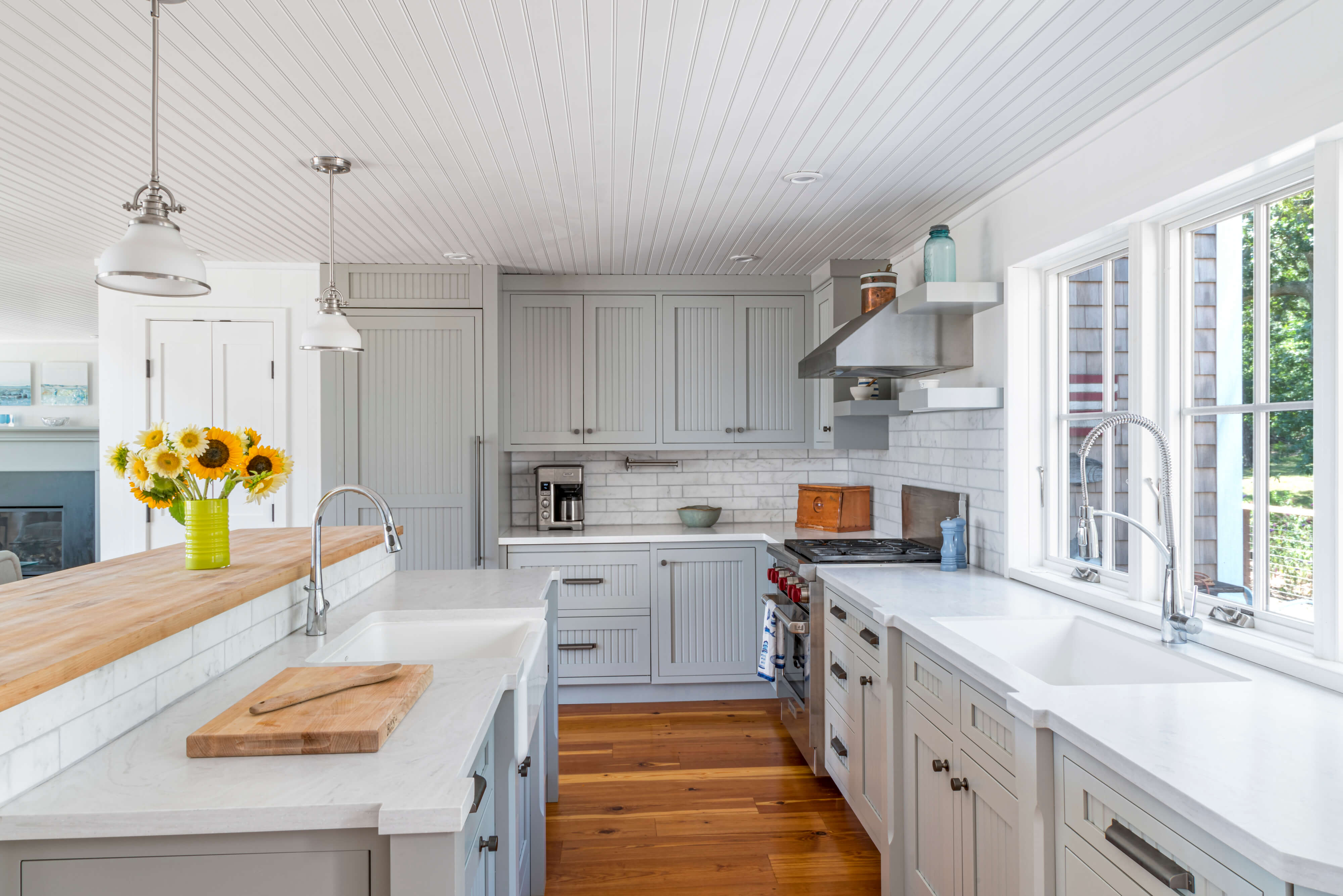 A delightful gray kitchen with cottage styled cabinet doors and a shiplap ceiling.