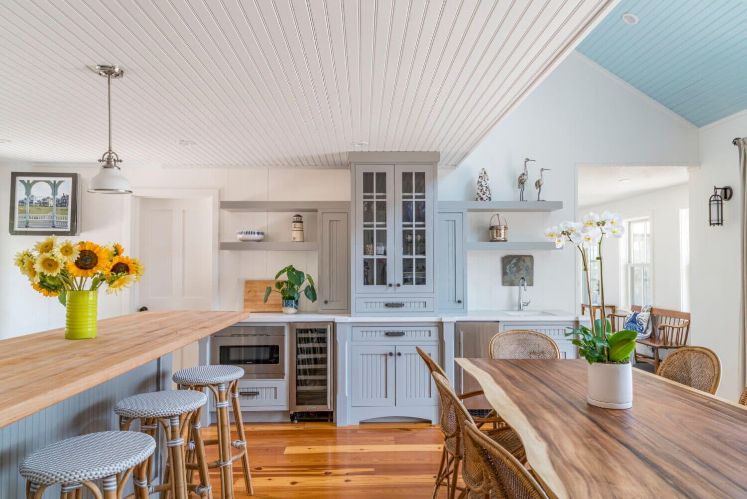 A dining room banquette area with counter space on both sides of a tall tower. One side is used as a beverage center, the other as a hutch for storing serveware.