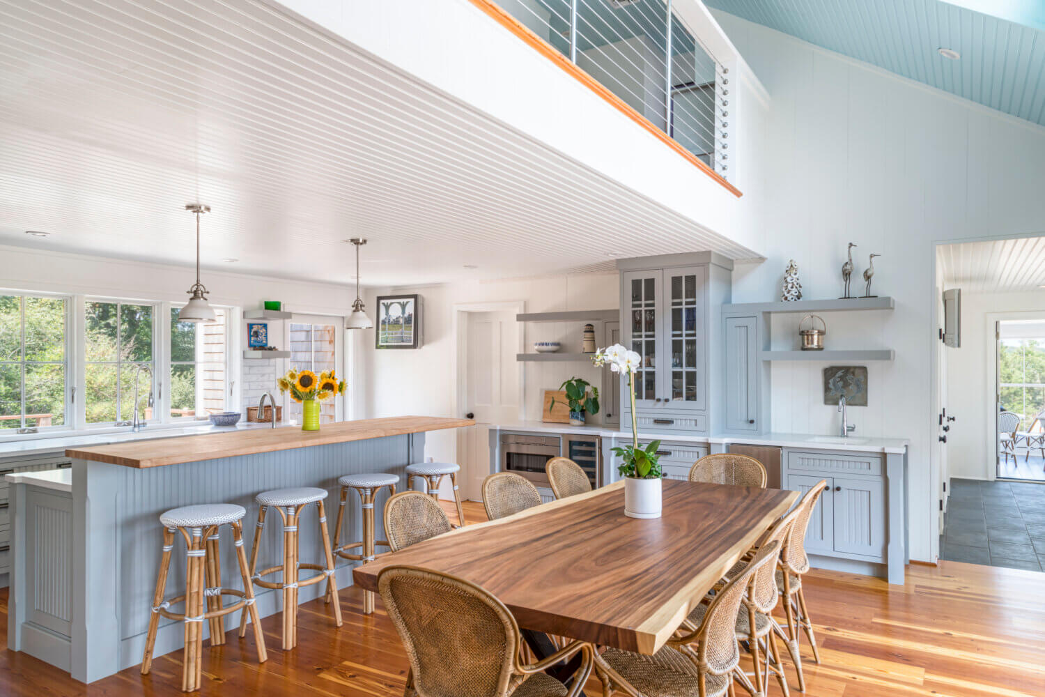 A cottage style kitchen with light gray inset cabinets has lots of seating for entertaining with the peninsula and dining room table side by side.