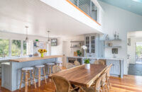 A cottage style kitchen with light gray inset cabinets has lots of seating for entertaining with the peninsula and dining room table side by side.