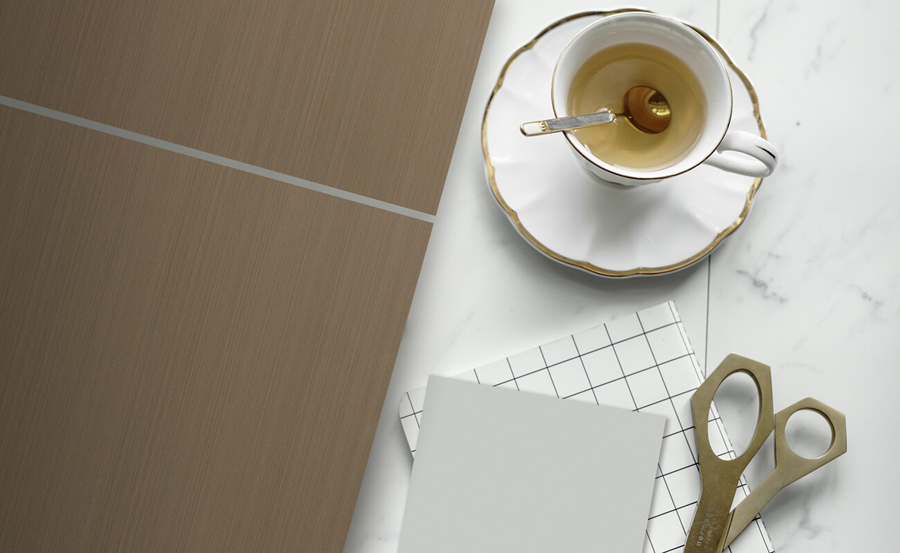 A glossy metallic-like bronze cabinet door style sitting on a quartz countertop with gold and brassy decor.