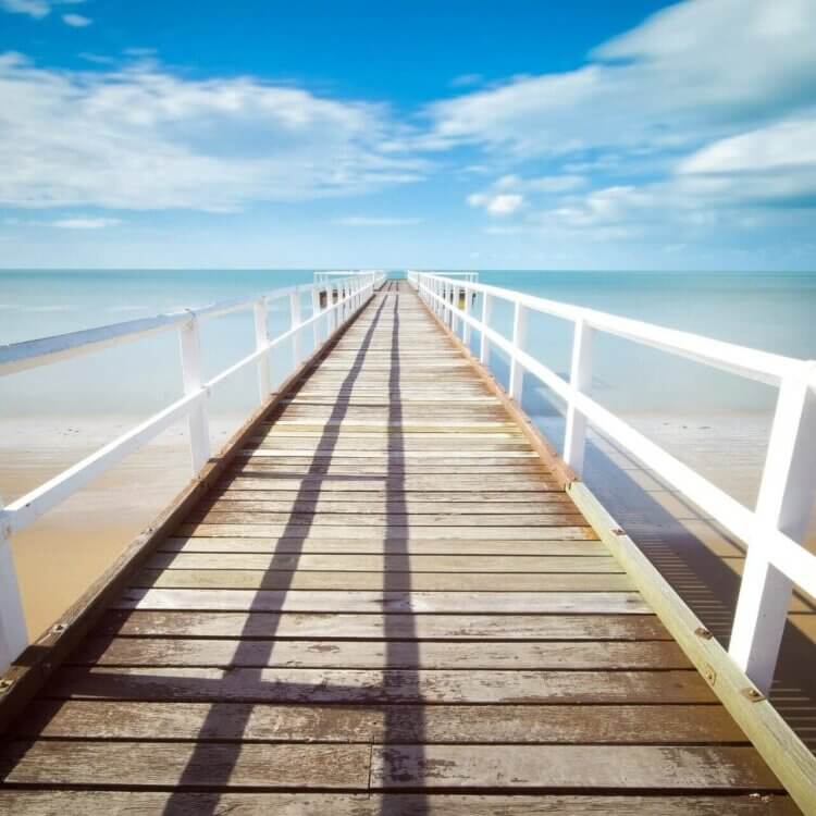 A cottage beach house dock with bright blue summer sky.