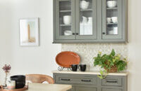 Plain glass insert for cabinet doors shown on a gray painted cabinet in a dining room.