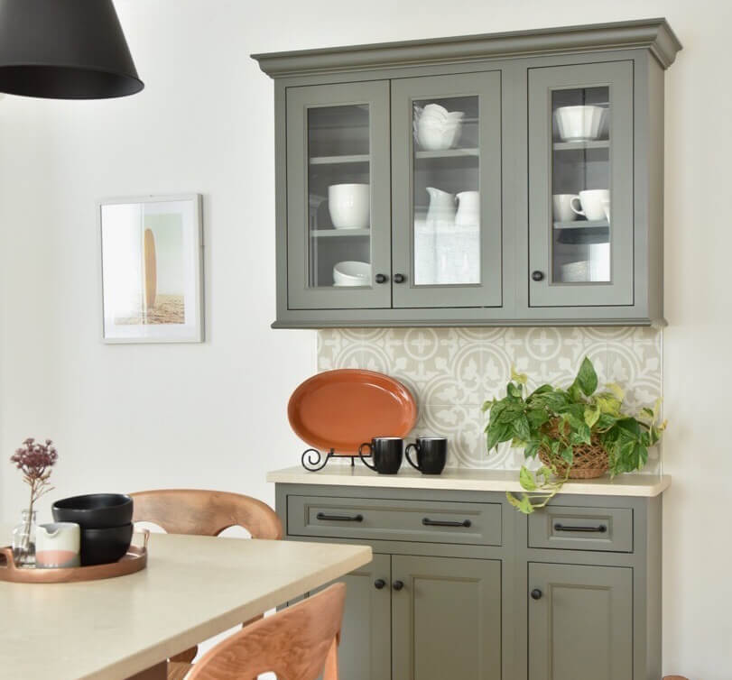 Plain glass insert for cabinet doors shown on a gray painted cabinet in a dining room.