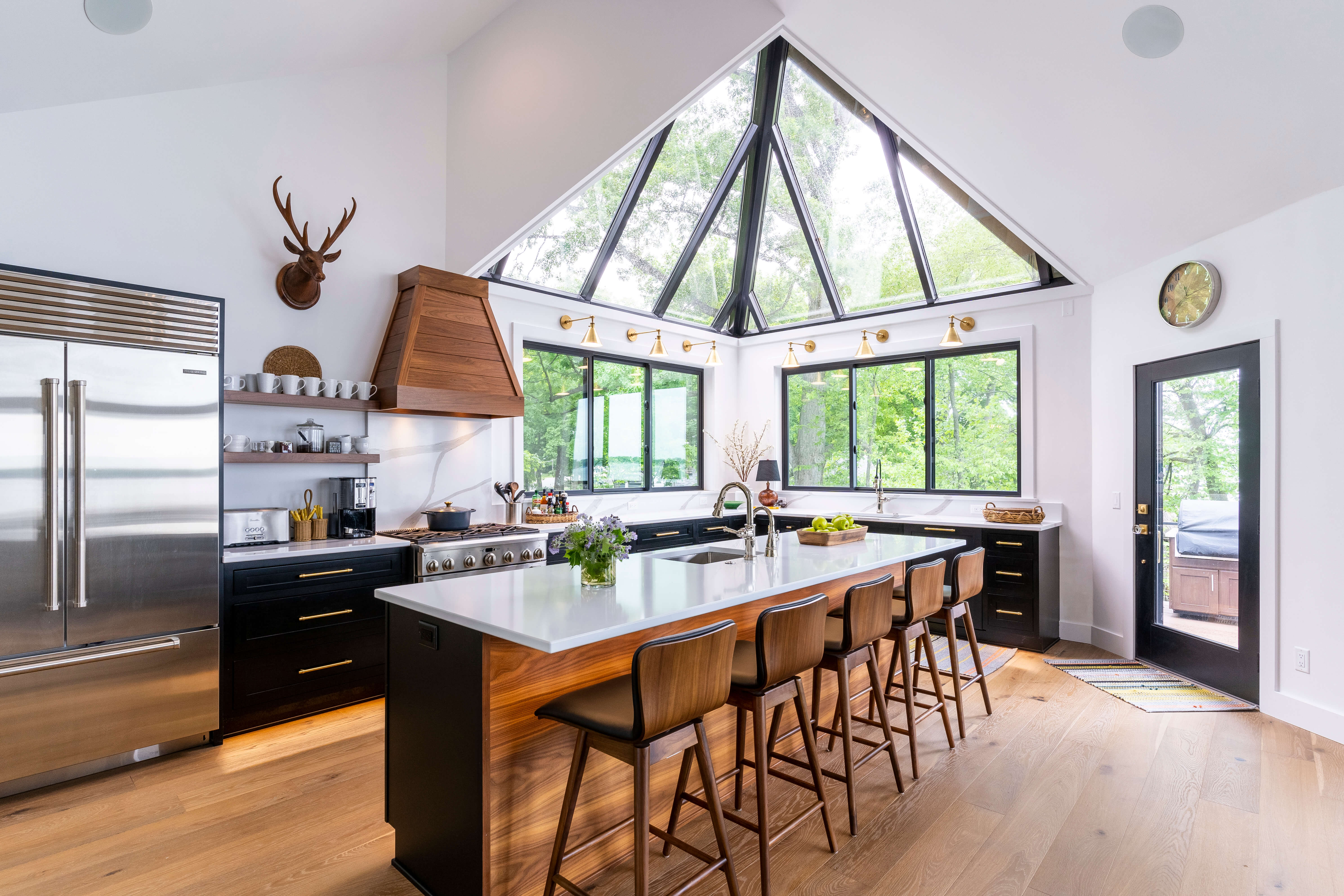 A black and white kitchen design with vaulted ceilings and black windows and doors.