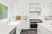 A crisp, bright white kitchen design with white painted shaker cabinets and stainless steel appliances.