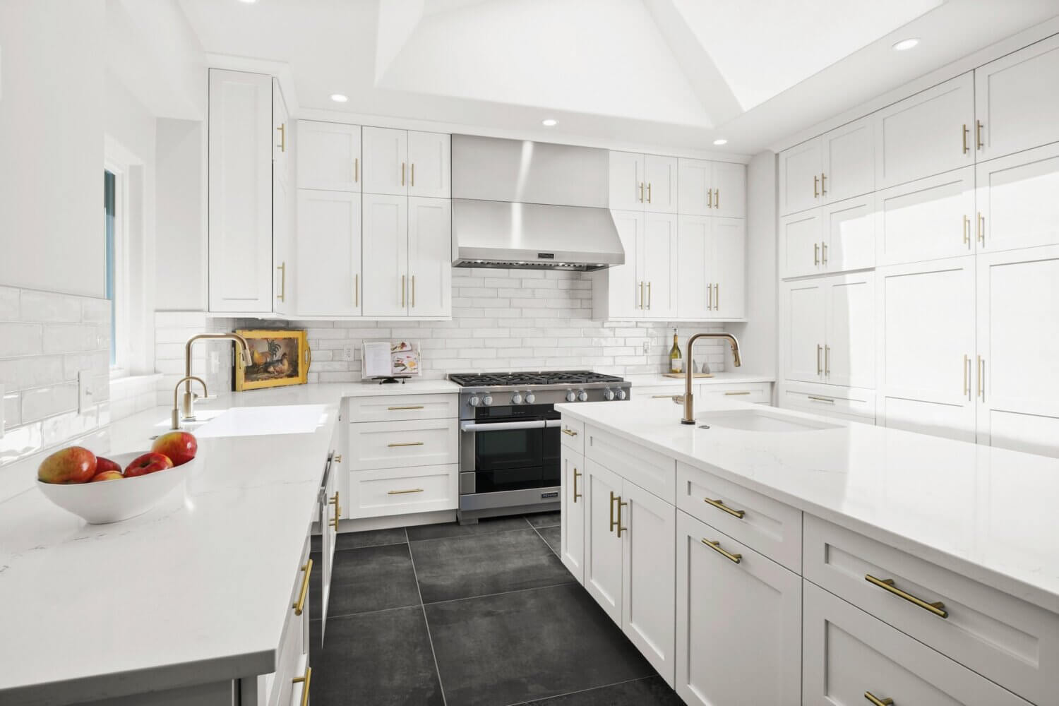 Bright white kitchen design with dark gray tiled floors. The cabinetry features modern shaker doors with a crisp, pure white paint color.