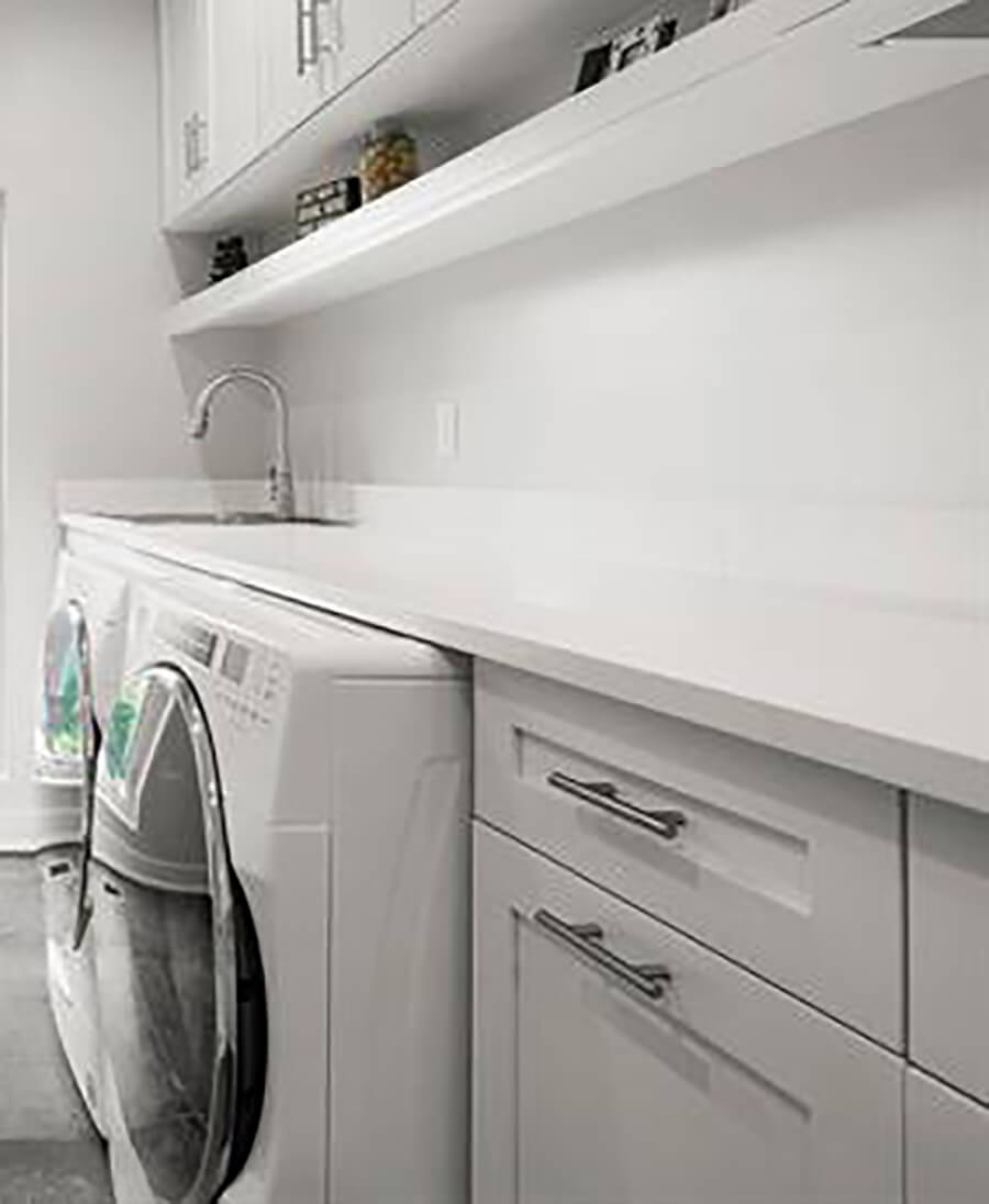 An all-white and bright laundry room with simple, sophisticated cabinets from Dura Supreme Cabinetry in a white painted finish.