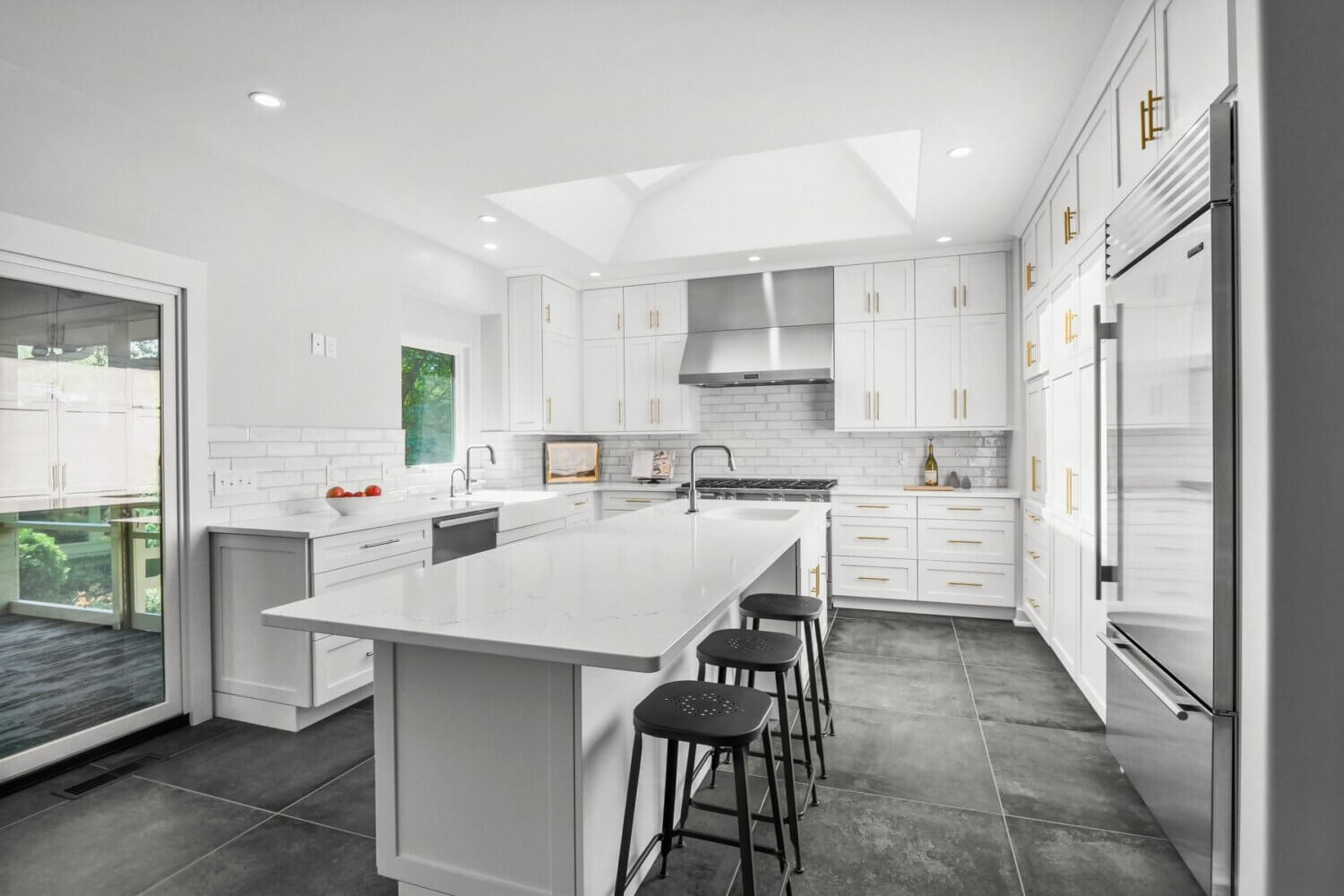 Dura Supreme Cabinetry in the Homestead Panel door style in “White” paint complements the quite diverse range of metals used throughout the kitchen from handles to appliances to island seating.