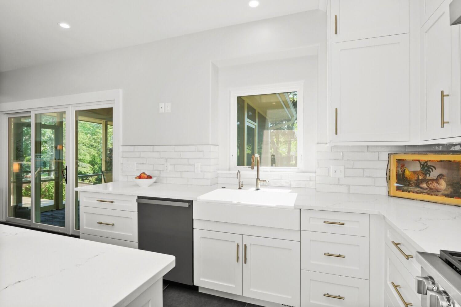 This all white kitchen uses pure white for the flat panel door cabinets, the apron sink, subway tile backsplash, countertops, etc.