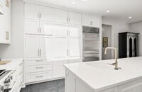 A wall of white painted shaker style cabinets in a transitional styled kitchen design.