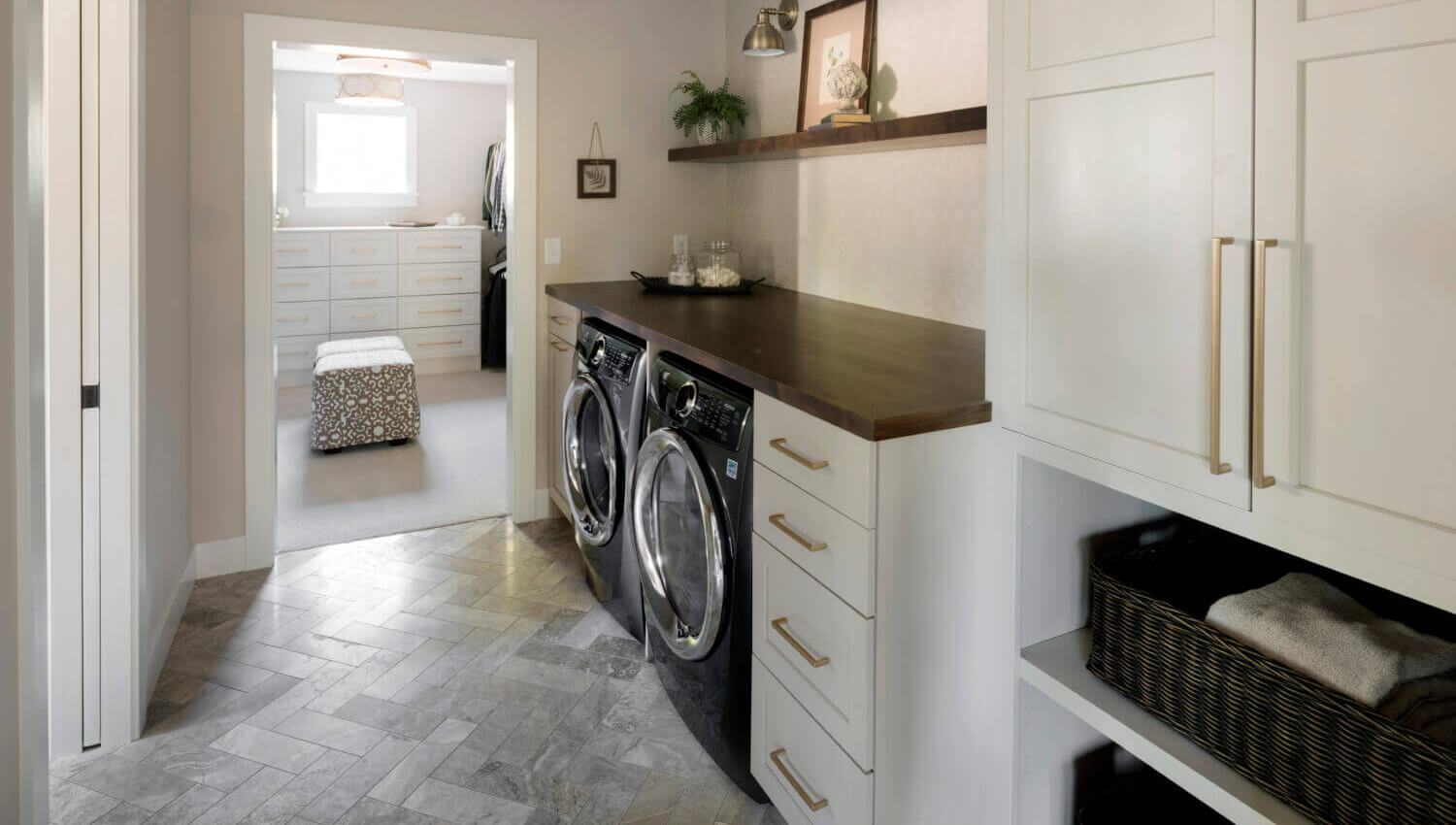 This laundry room is part of the master bedroom's grand walk-in closet. The off-white painted cabinets feature a classic shaker door style.