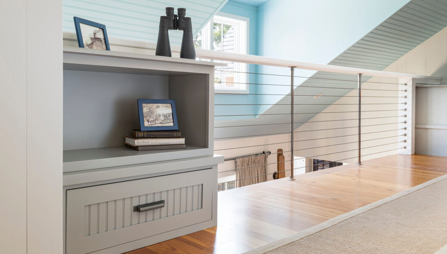 Gray cottage beaded cabinets in a loft hallway in a beach cottage home.