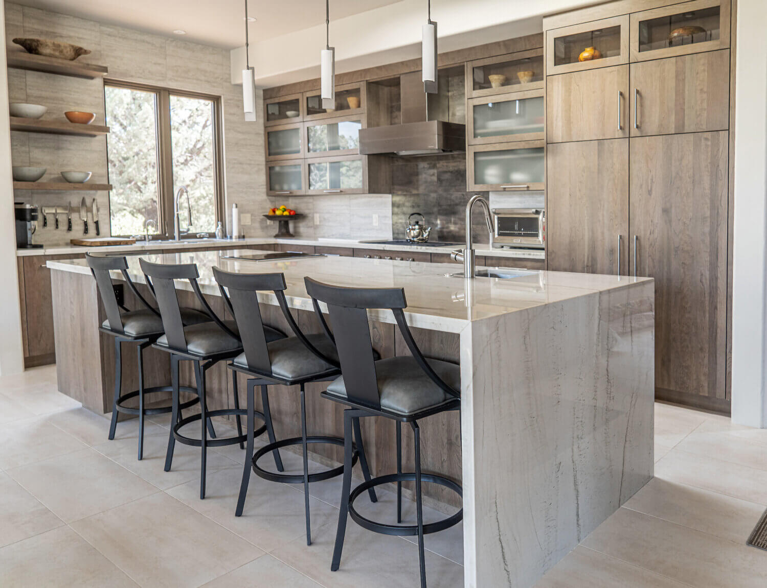 This modern kitchen has a waterfall kitchen island, seating for four, and stunning light gray-brown stained cabinets from Dura Supreme.