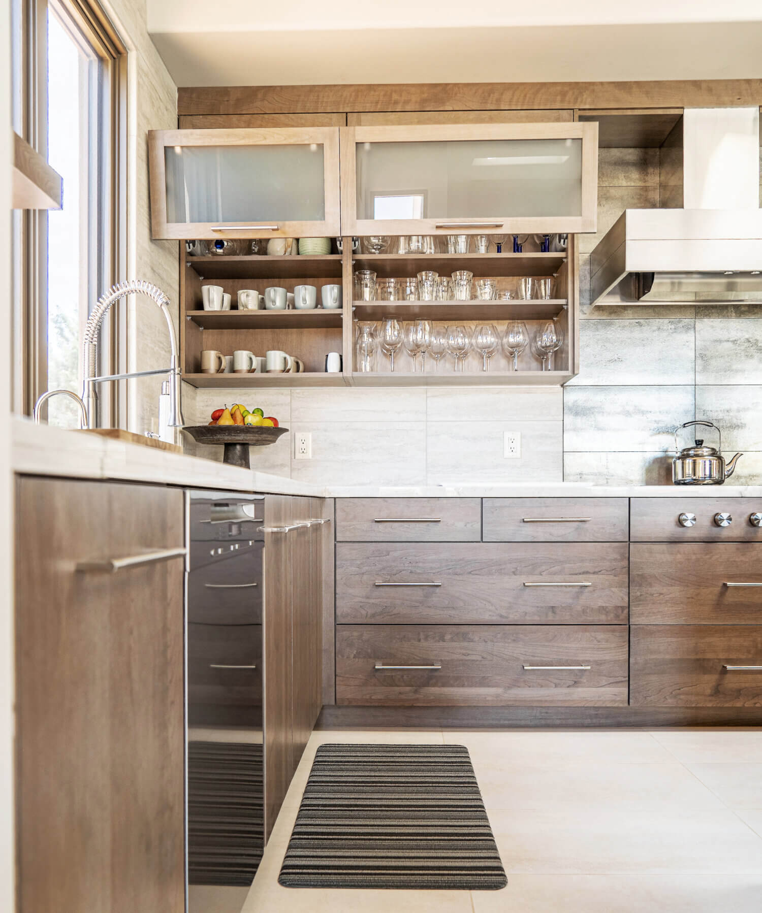 A straight on view of the open wall cabinets with lift-up bi-fold doors and frosted glass doors that have lots of room for glassware storage.