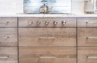 A close up of the flat, slab cabinet doors with a light gray-brown stain color.