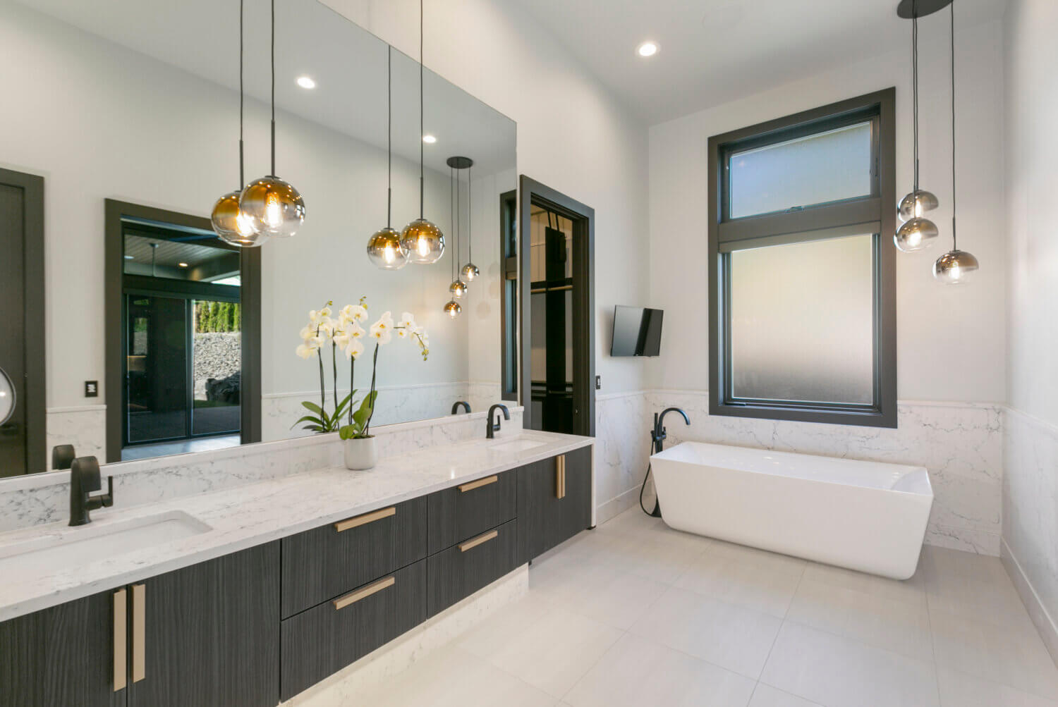 A sleek, modern bathroom design with a black and white color palette and premium contemporary materials and finishes. The long stretching black cabinetry is wall-hung to look as if it’s floating above the bathroom floor delivers heaps of drama to this master bathroom featuring Dura Supreme’s black “Basalt” Textured TFL on the Tempo-Vertical door style.