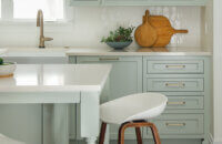 A soft pastel green painted kitchen and kitchen island.