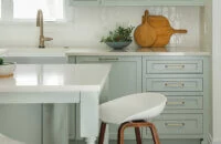 A soft pastel green painted kitchen and kitchen island.