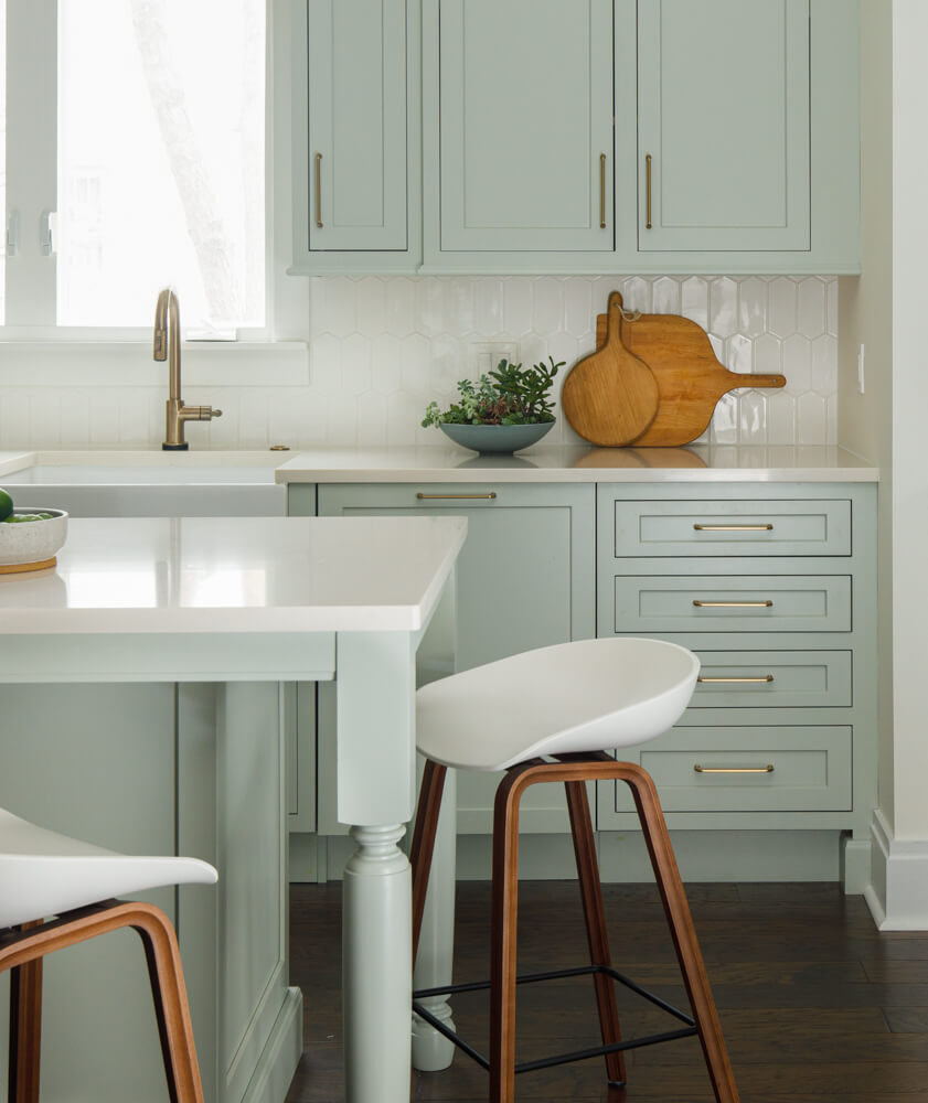 A soft pastel green painted kitchen and kitchen island.