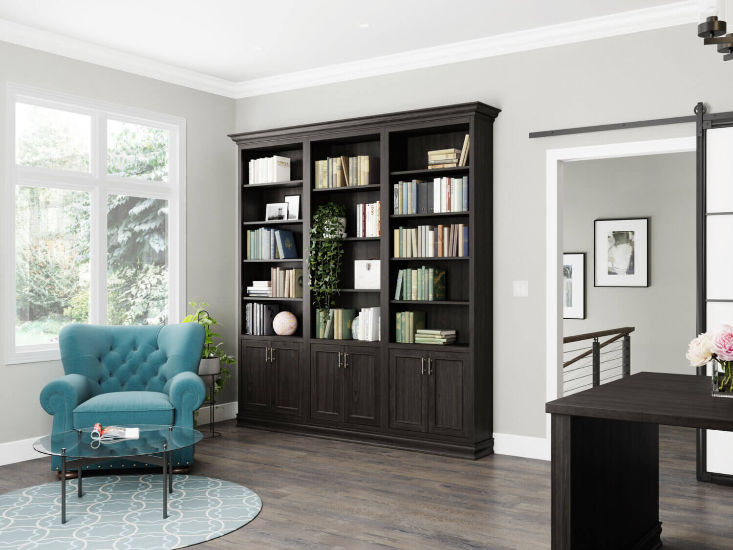 A wall of the home office has a built-in bookcase with cabinets that has a dark stain that matches the office desks.