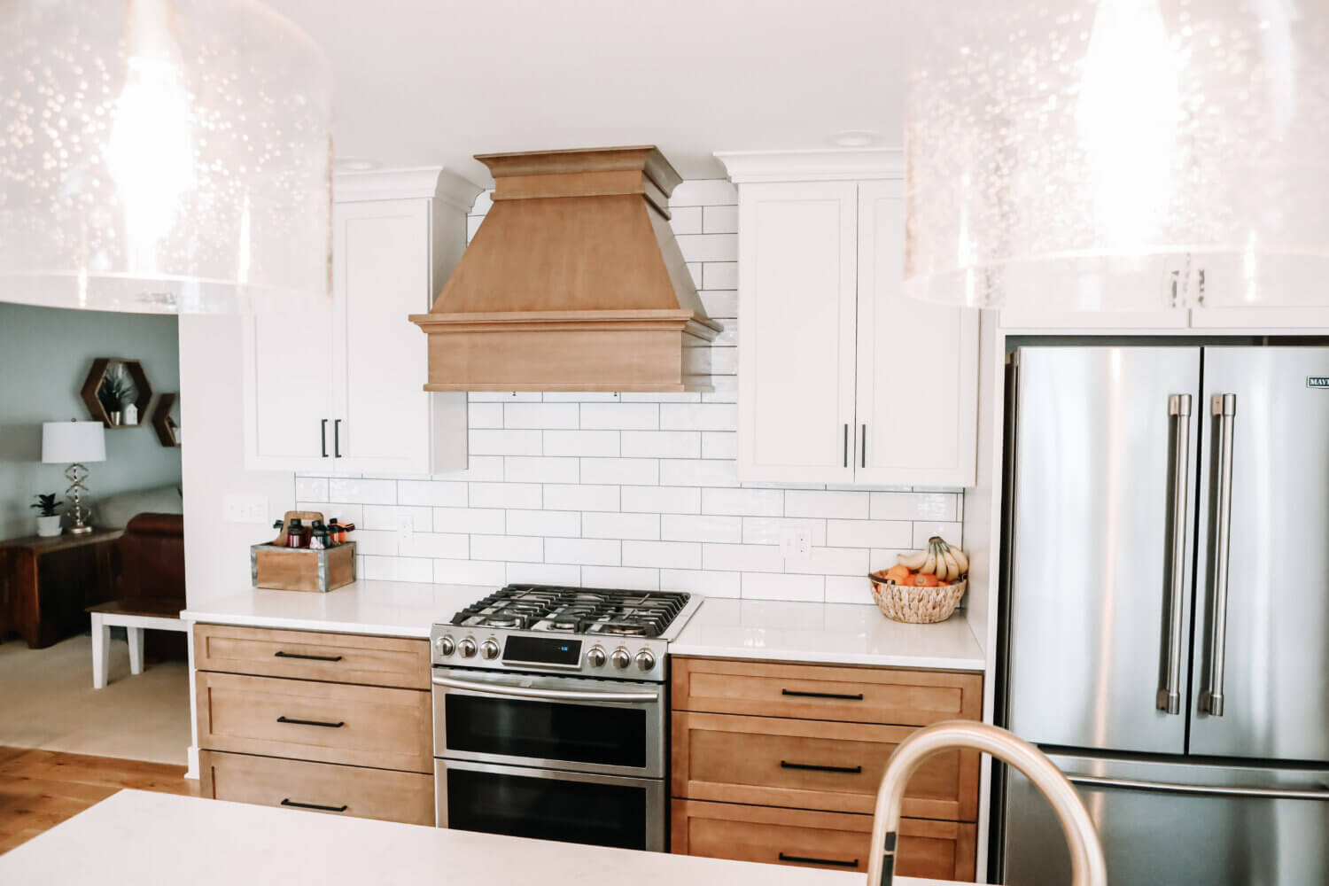 A beautiful two-toned kitchen remodel with white painted cabinets and warm stained wood. An independent wood hood features a modern style.